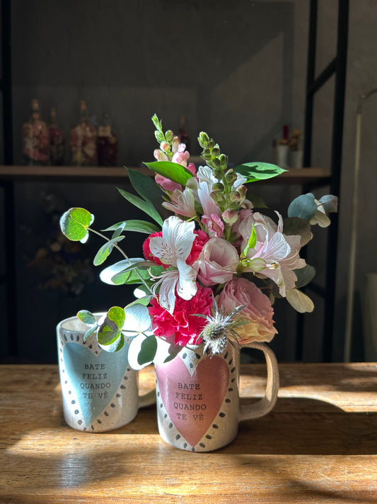 Arranjo de flores na caneca "bate feliz quando te vê"